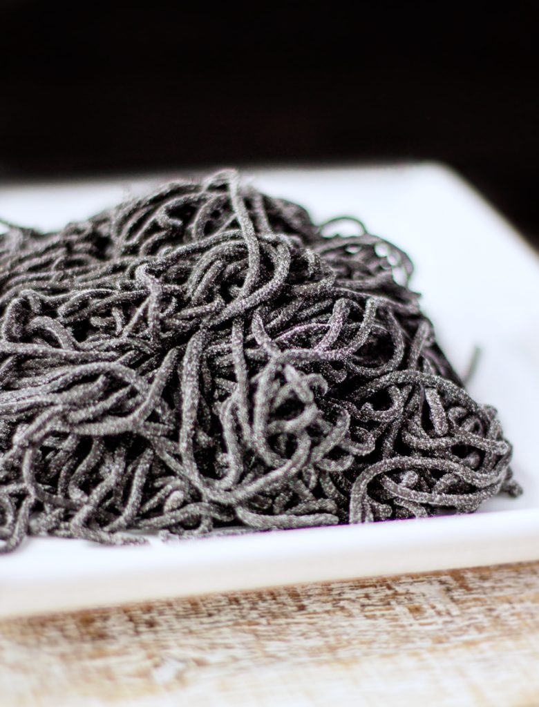 black homemade squid ink pasta noodles lightly dusted in flour, homemade pasta al nero de seppia